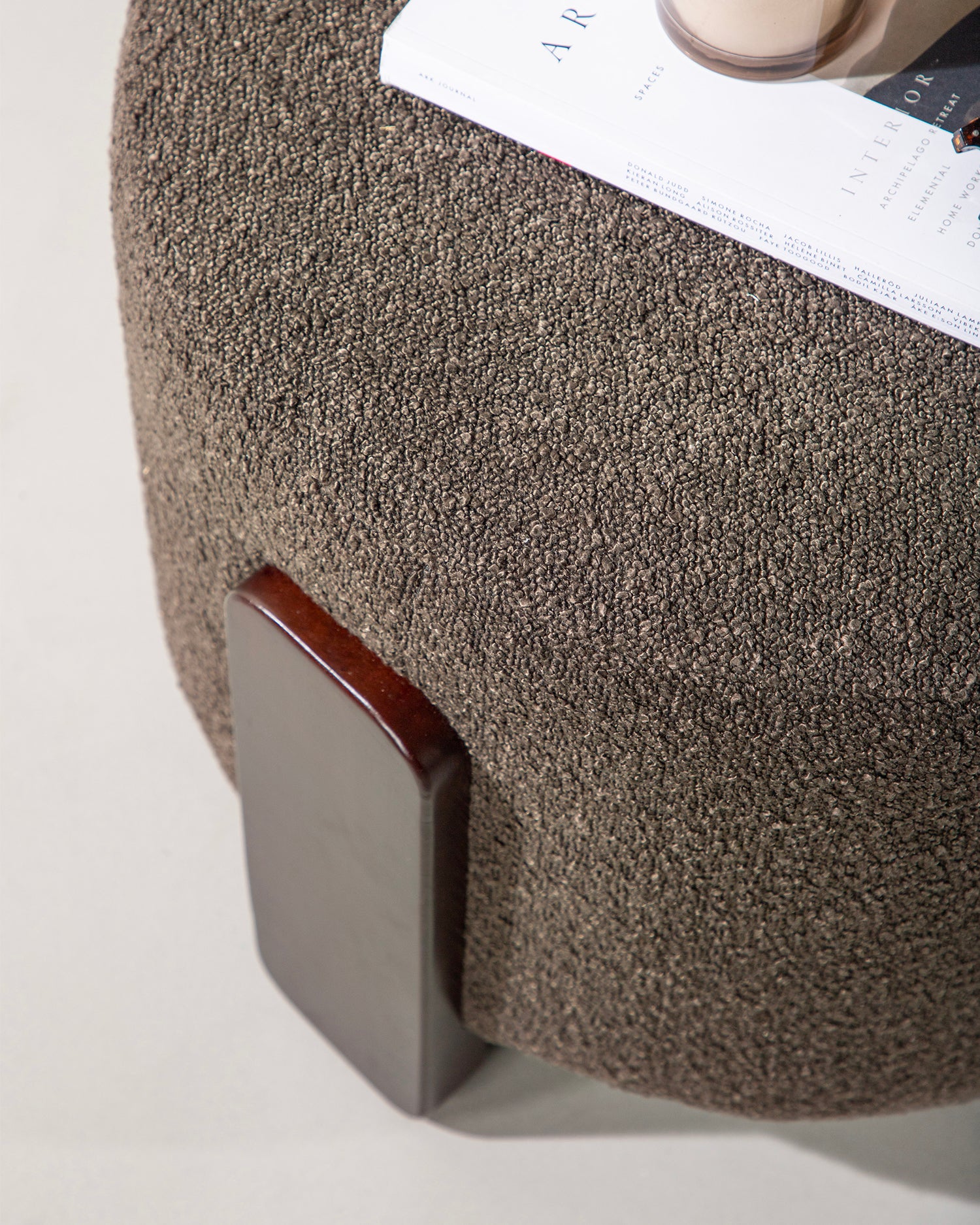 Pouf imbottito in bouclè con piedini in legno Coffey